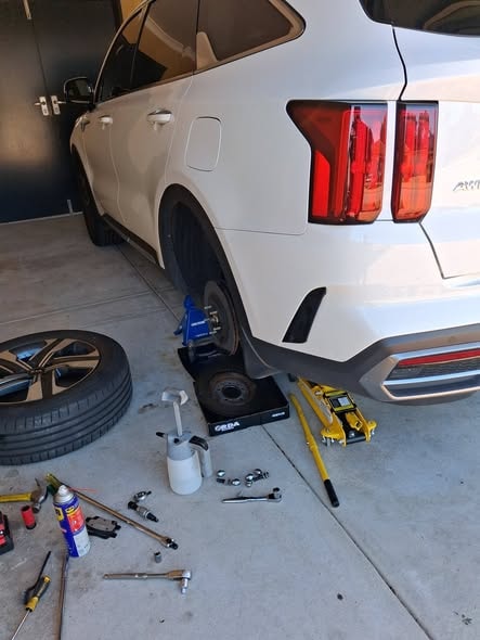 Brake service in progress — wheel removed, tools laid out on a Perth driveway
